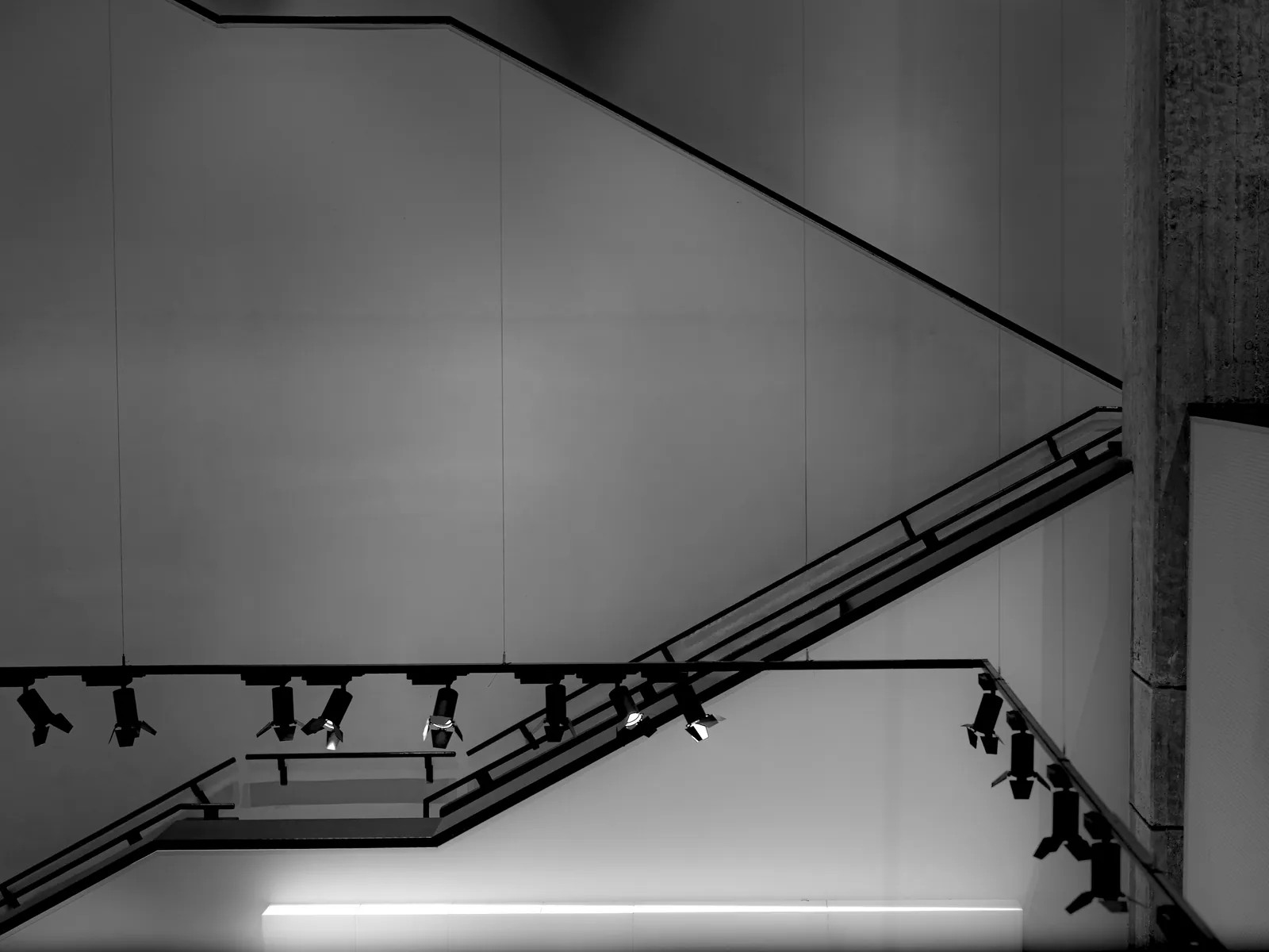 Modern minimalist staircase with geometric steel structure and concrete, high contrast against pale walls