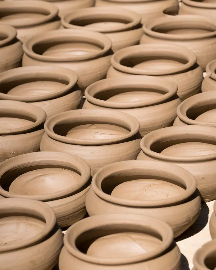 A potter shaping a bowl on the wheel, hands wet with clay