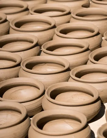 A potter's hands shaping wet clay on the wheel