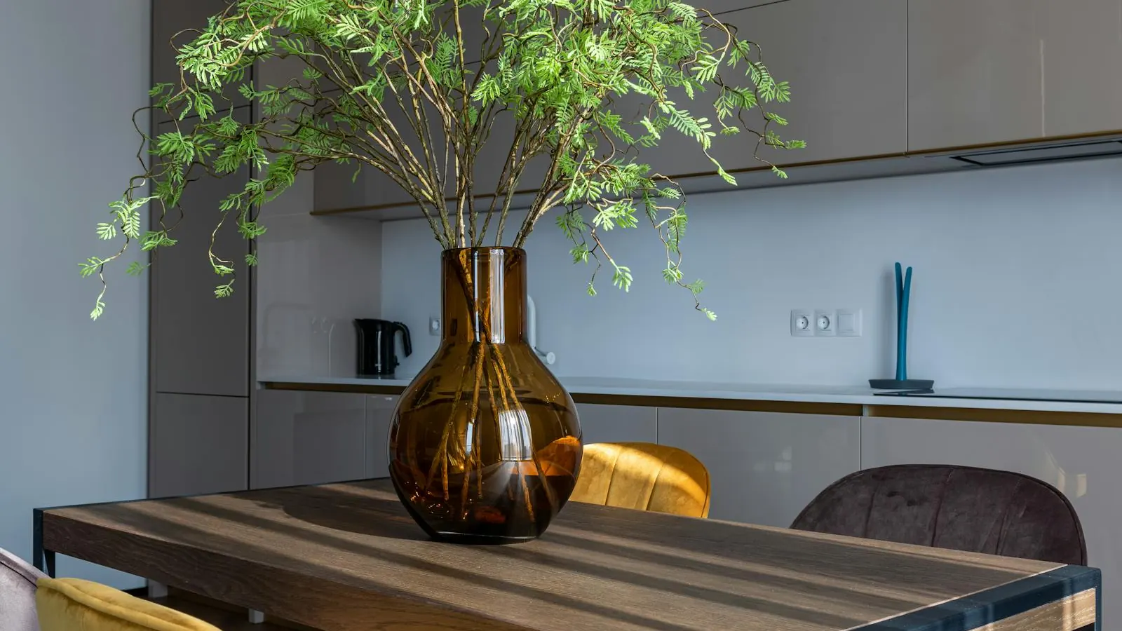 A calm interior shelf in warm afternoon light, holding ceramic vessels and a single linen cloth