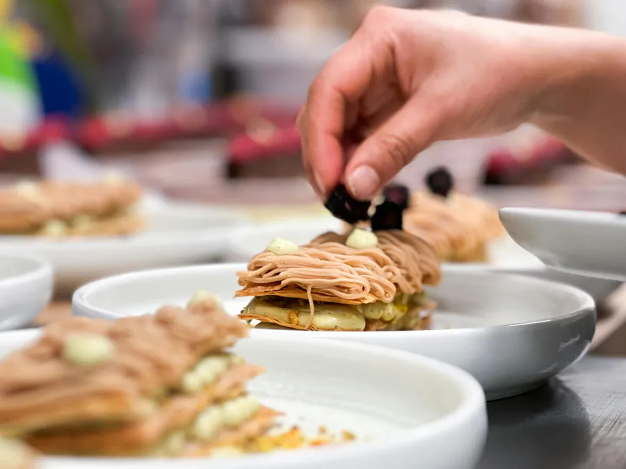 Chef's hand placing a garnish on an elegant chestnut dessert