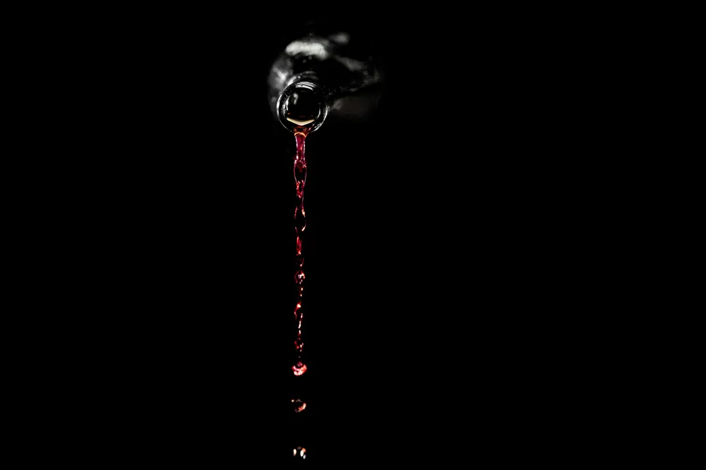 Red wine poured against darkness