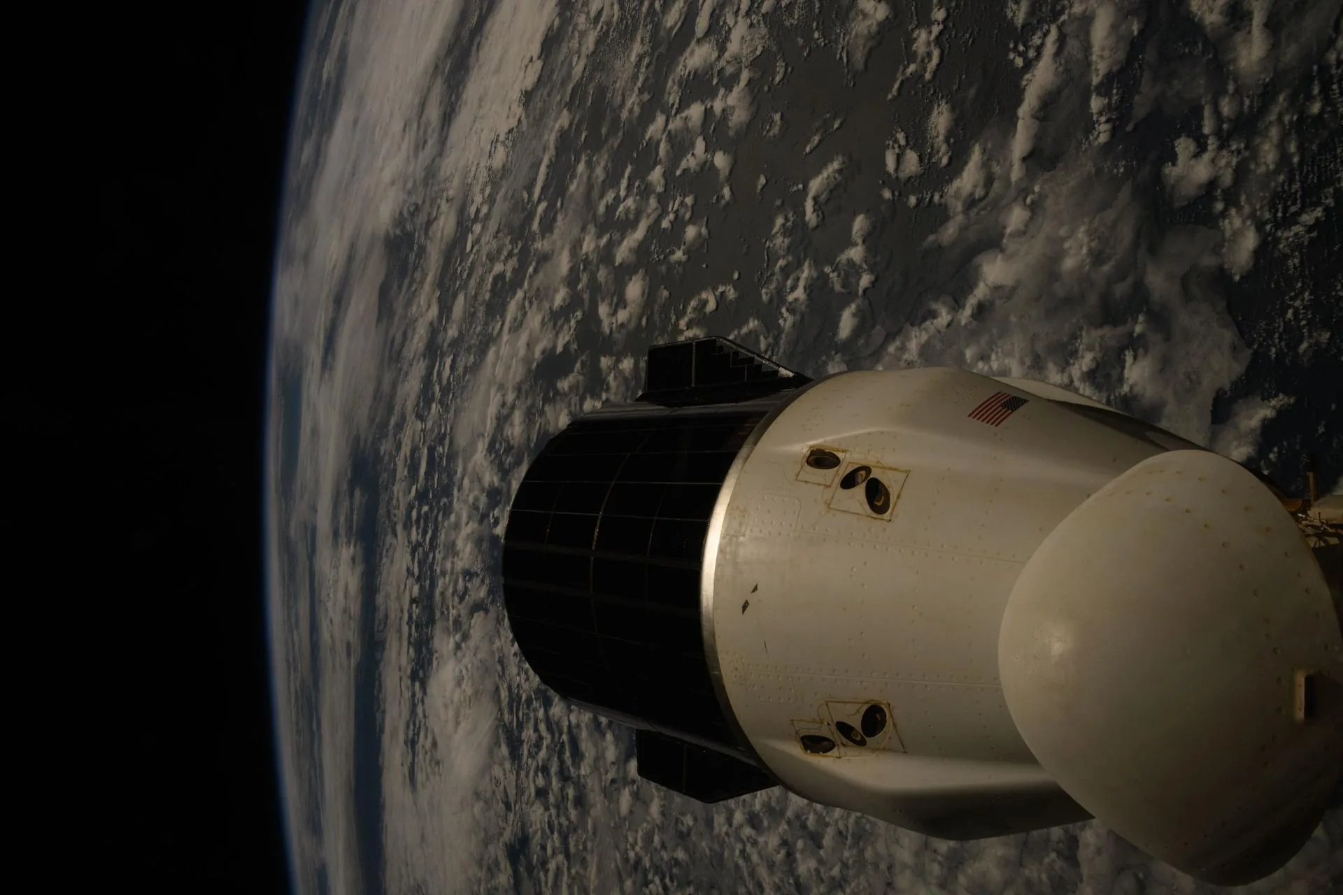 The APSIS-VII crew vehicle photographed in low Earth orbit, the planet's atmosphere a thin blue line behind it.