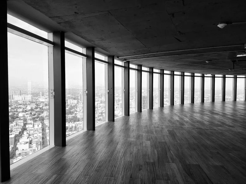Empty upper-floor office with floor-to-ceiling windows overlooking the city